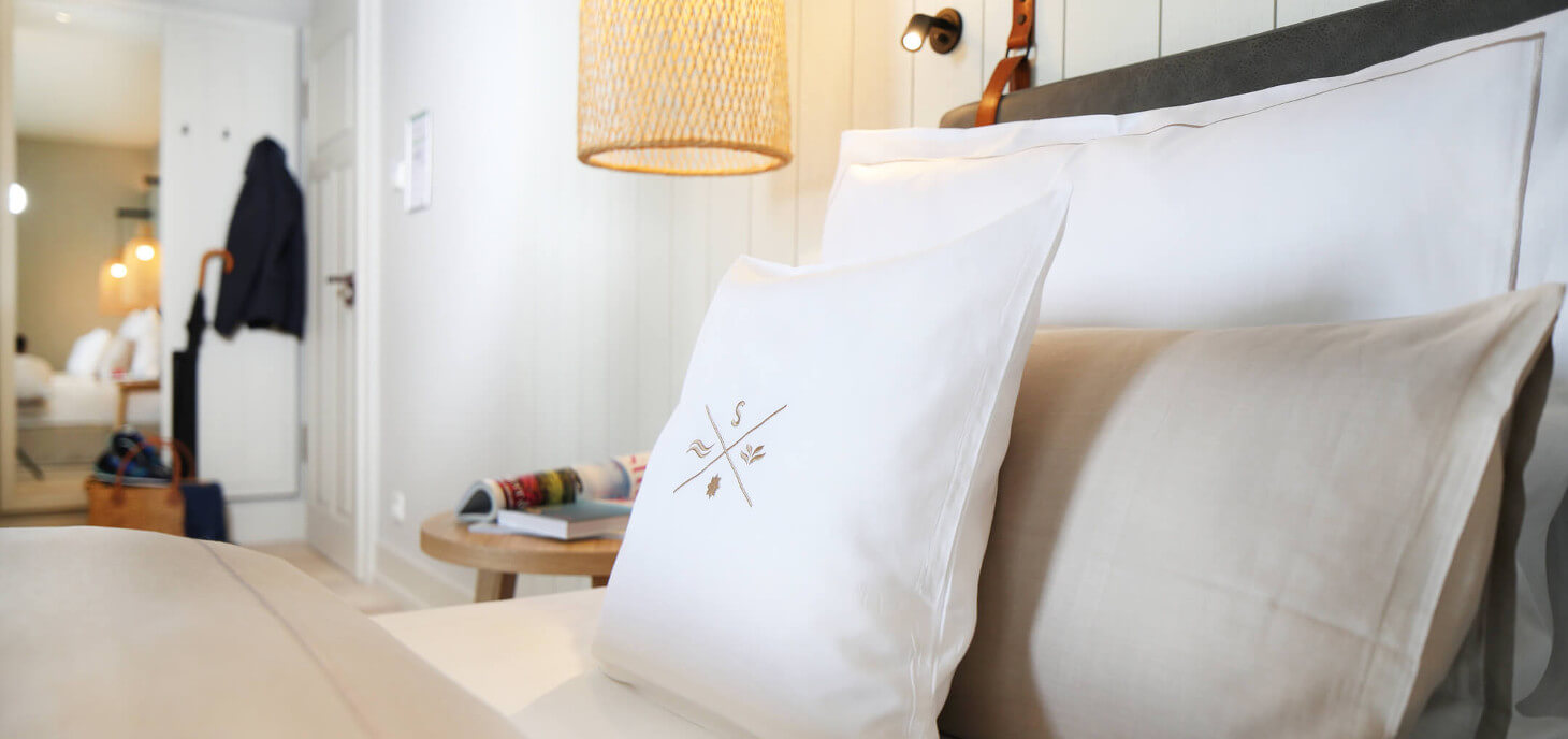 Blick auf ein Bett mit vielen Kissen in einem der Zimmer im Hotel Landhaus Severin*s Morsum Kliff