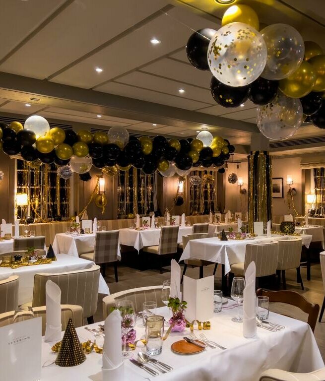 Elegantes Restaurant im Landhaus Severin*s, dekoriert mit gold-schwarzen Luftballons und festlich gedeckten Tischen an Silvester.