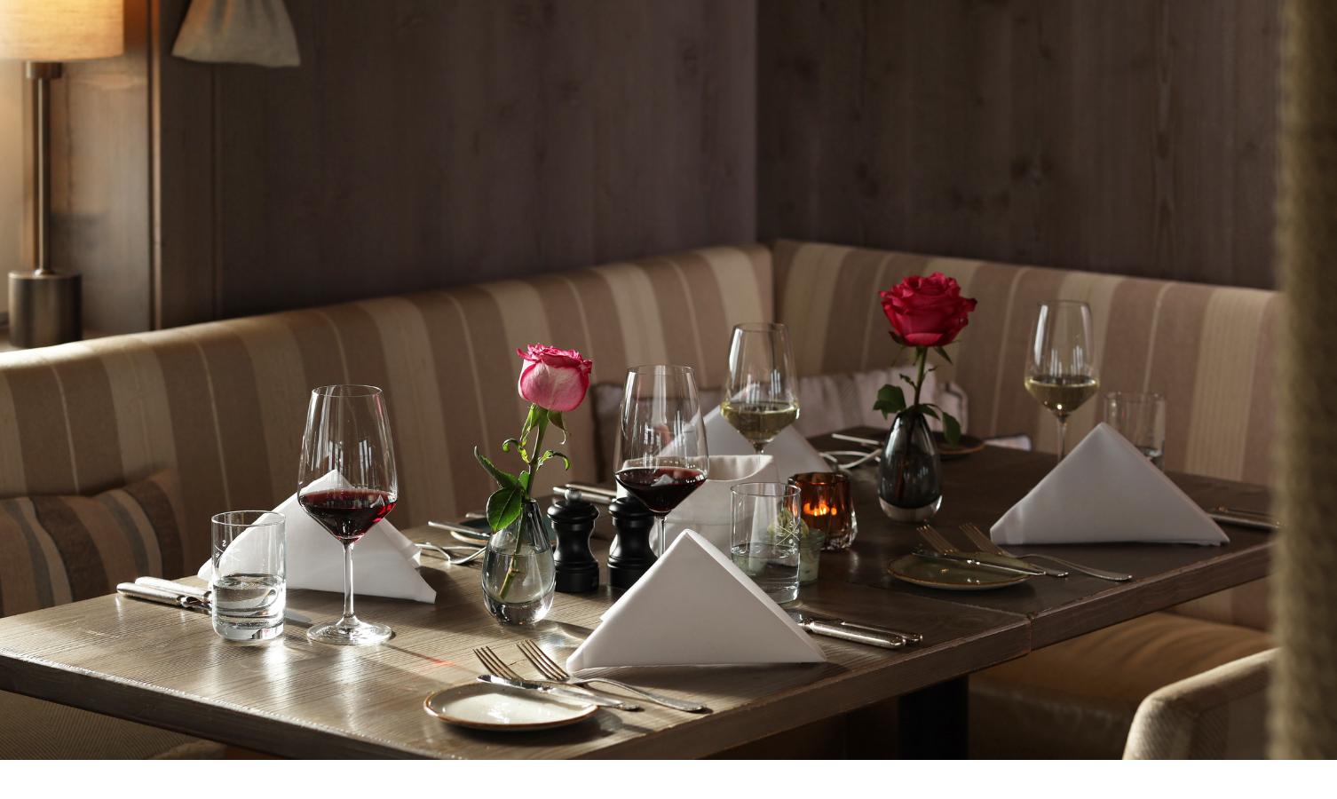 Eleganter Restauranttisch mit Weingläsern, weißen Servietten und Rosen im Hotel Landhaus Severin*s Morsum Kliff.