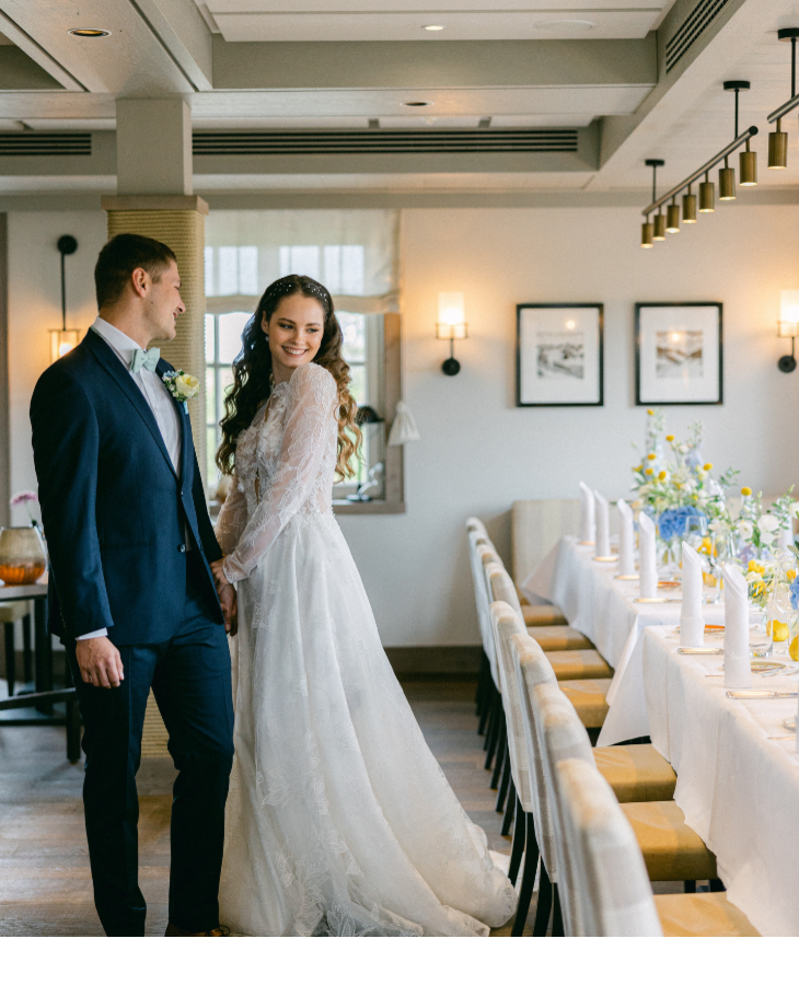 Brautpaar – Landhaus Severin*s Ein Paar in Hochzeitskleidung steht in einem elegant dekorierten Speiseraum des Landhaus Severin*s Morsum Kliff.
