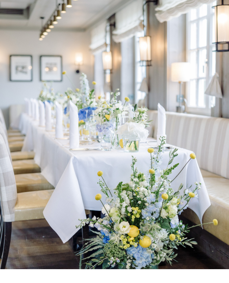 Eleganter, gedeckter Tisch mit blauen und gelben Blumenarrangements in einem hellen, stilvollen Raum im Landhaus Severin*s.