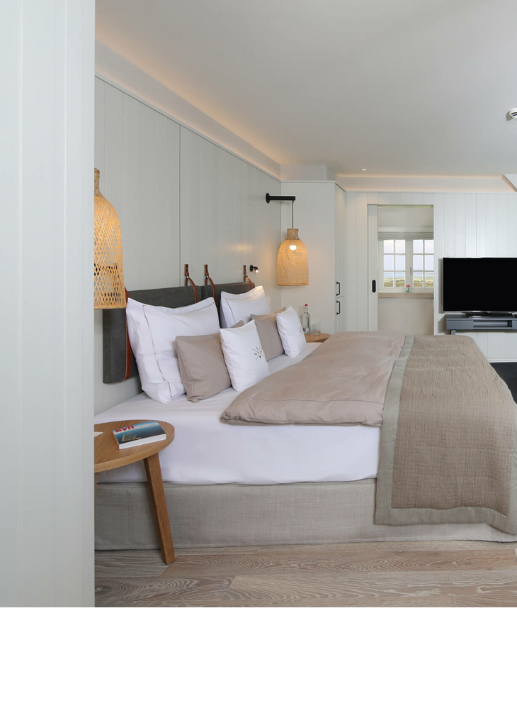 Helles, modernes Hotelzimmer mit Doppelbett, Sitzbereich, TV und Dachschräge im Landhaus Severin*s Morsum Kliff.