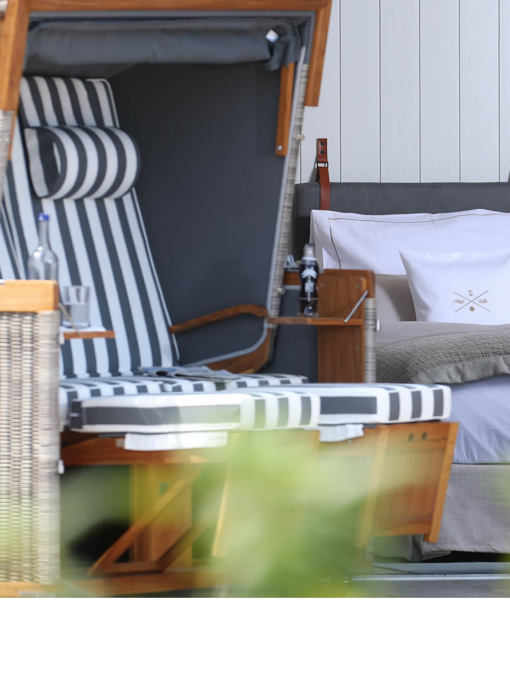 Strandkorb und gemütliches Bett im Hotel Landhaus Severin*s Morsum Kliff, Sylt, durch offene Tür sichtbar.