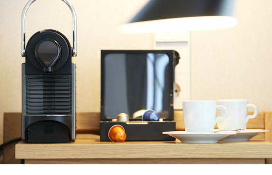 Kaffeemaschine mit Kapseln und zwei weißen Tassen auf Holzablage im Landhaus Severin*s Morsum Kliff Hotelzimmer.