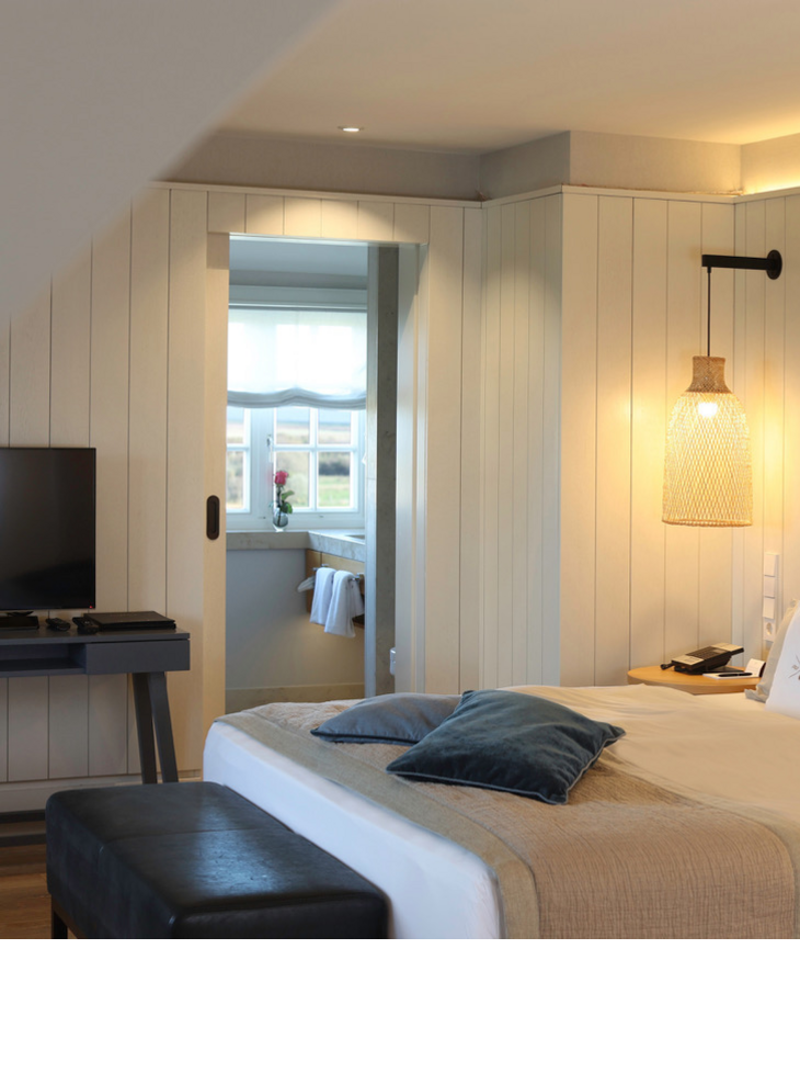 Gemütliches Hotelzimmer im Landhausstil mit Doppelbett, TV, stilvoller Beleuchtung und Fensterblick im Landhaus Severin*s.