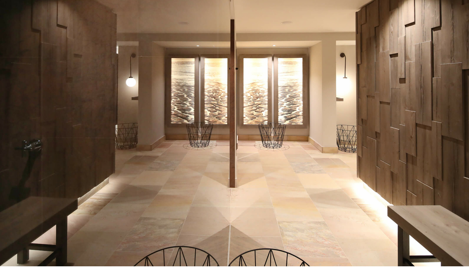 Wellnessbereich im Landhaus Severin*s Morsum Kliff auf Sylt Moderner, eleganter Hotel-Flur mit Holzwänden, stilvollen Lampen und großem Fenster mit Naturmotiv im Landhaus Severin*s.