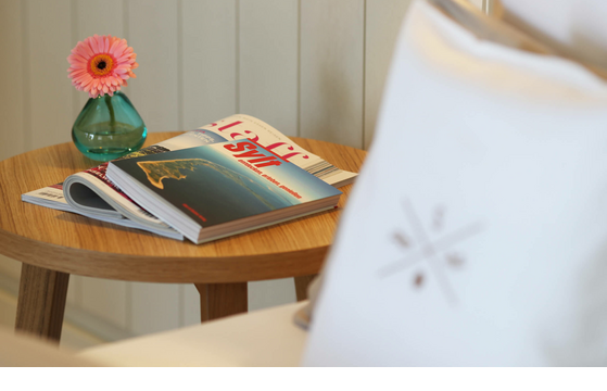 Holztisch mit Magazin über Sylt und rosa Blume in Vase im Hotel Landhaus Severin*s Morsum Kliff.