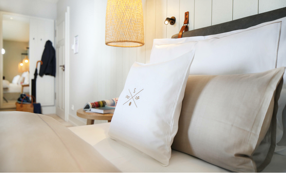 Gemütliches Hotelzimmer mit eleganter Bettwäsche, warmem Licht und stilvoller Dekoration im Landhaus Severin*s Morsum Kliff.