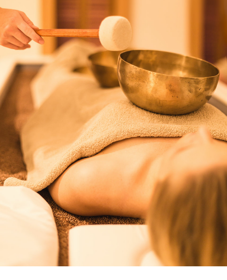 Person genießt Klangschalen-Massage im Severin*s Resort & Spa, Sylt. Entspannung mit warmen Tönen und sanfter Atmosphäre.