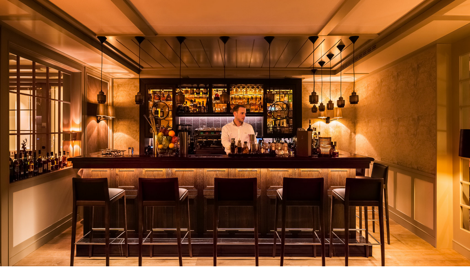 Elegante Hotelbar im Severin*s Resort & Spa auf Sylt, mit gemütlicher Beleuchtung und einem Barkeeper hinter der Theke.