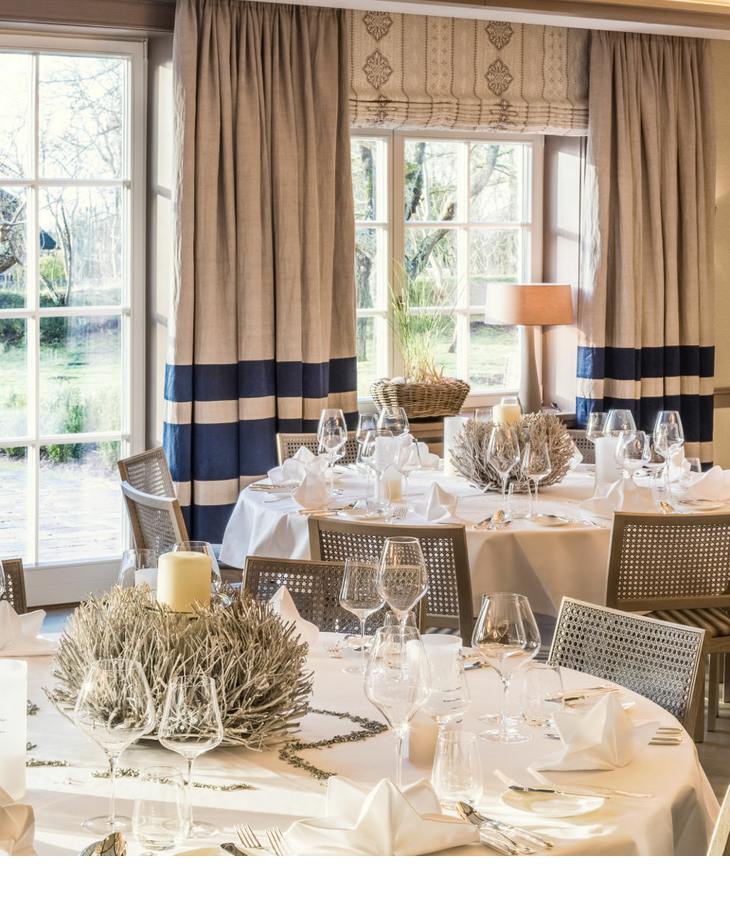 Elegantes Restaurant mit gedeckten Tischen, weißen Tischdecken und großen Fenstern im Severin*s Resort & Spa auf Sylt.