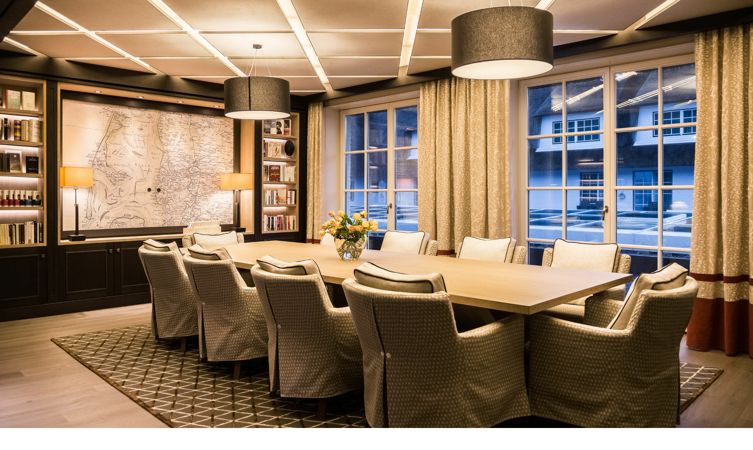 Eleganter Konferenzraum mit großem Tisch, gepolsterten Stühlen, Bücherregalen und großer Karte an der Wand im Severin*s Resort.