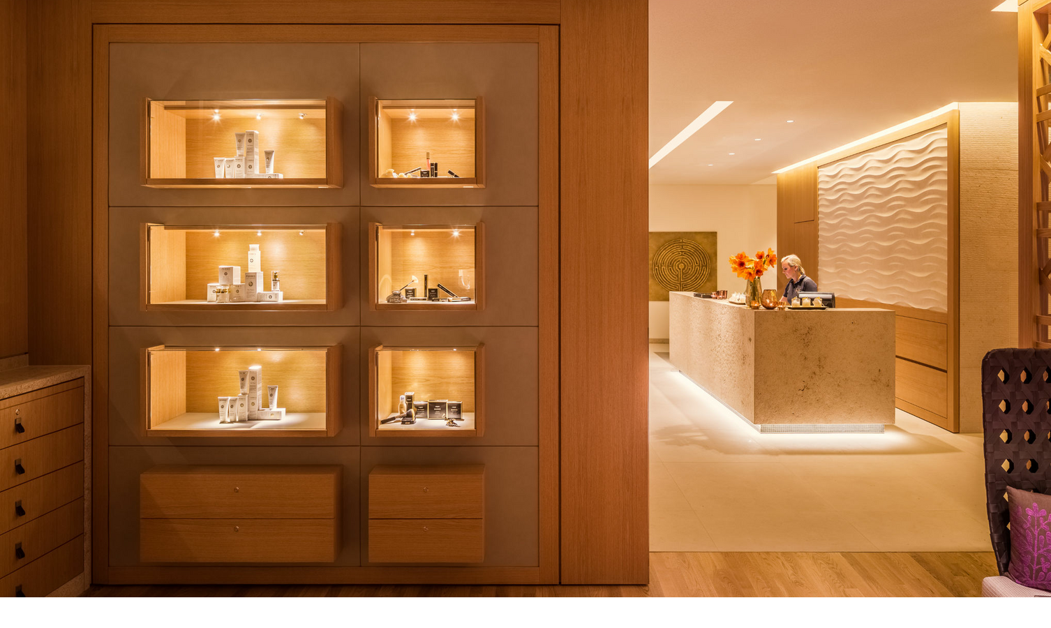 Elegante Hotelrezeption mit beleuchteter Vitrine und warmem, einladendem Ambiente im Severin*s Resort & Spa auf Sylt.