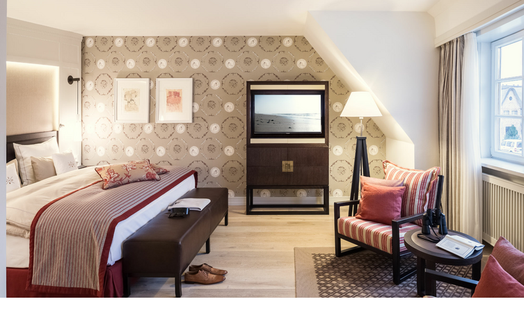 Elegantes Hotelzimmer mit Doppelbett, stilvoller Sitzecke, dekorativer Tapete und Fensterausblick im Severin*s Resort & Spa.