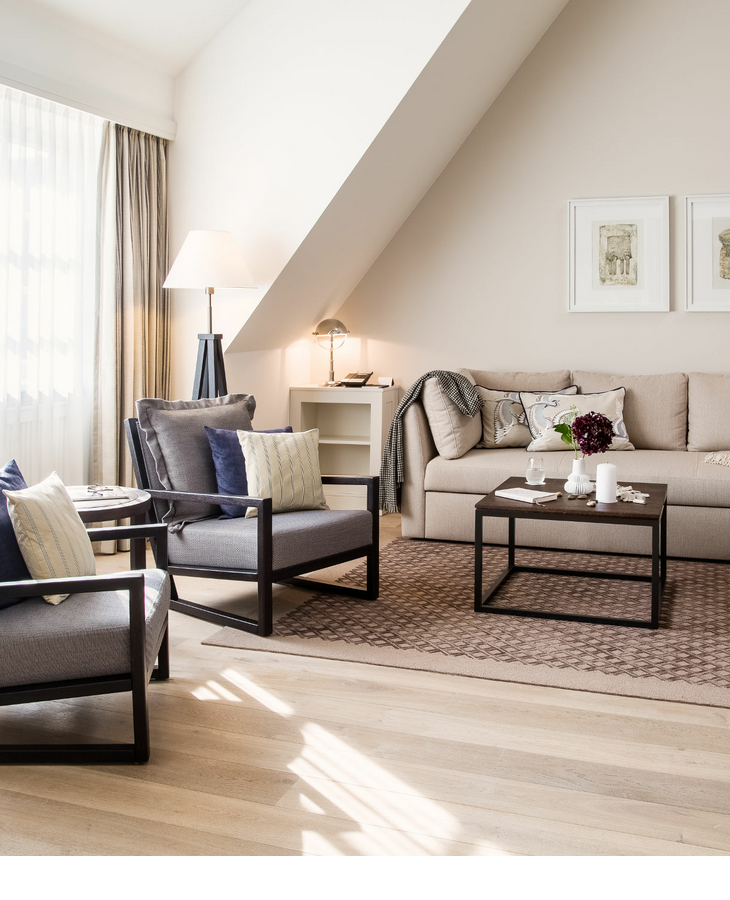 Helles, elegantes Wohnzimmer im Severin*s Resort & Spa mit Sofa, Sesseln, Tisch und stilvoller Dekoration.