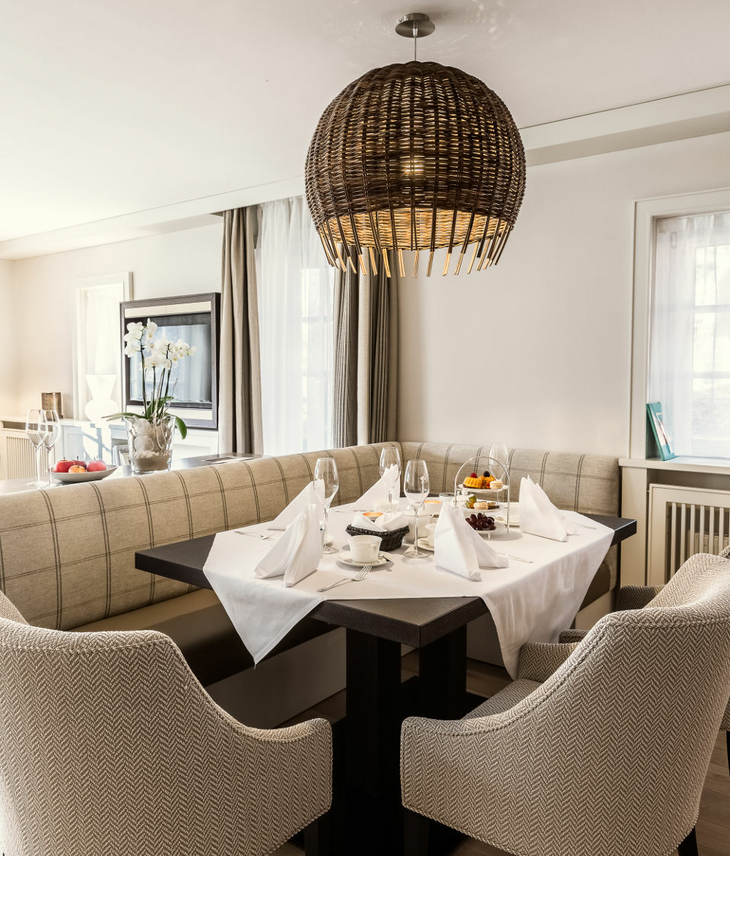 Eleganter Essbereich im Severin*s Resort & Spa mit gedecktem Tisch, gemütlichen Sesseln und hängender Korblampe.