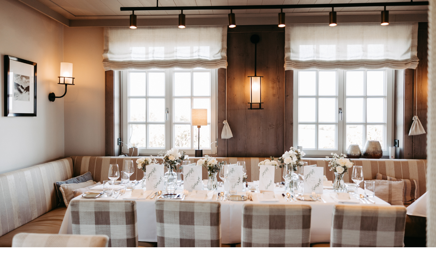 Gemütlicher Essbereich im Landhausstil mit gedecktem Tisch, Blumenarrangements und großen Fenstern im Hotel Landhaus Severin*s.